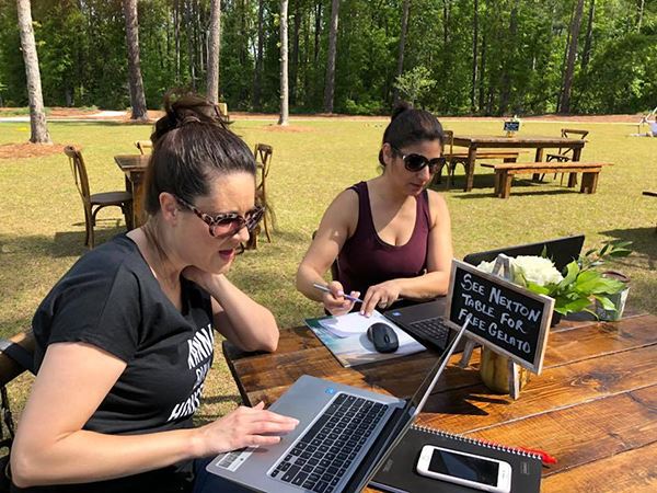 Women working on computers at picnic table in park at Nexton.