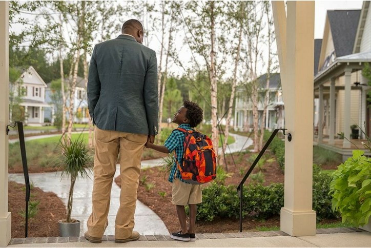 Adult_and_child_with_backpack_holding_hands_on_porch.jpg