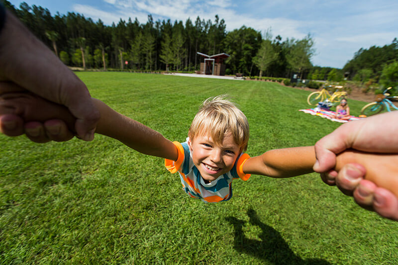 Little boy being spun around in park at Nexton